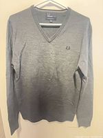 Front view of grey V-neck sweater on hanger