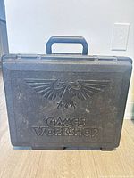 Front view of black Games Workshop Warhammer carrying case showing handle and logo