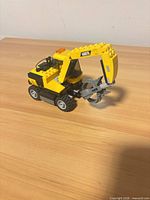 Side view of yellow LEGO 60075 excavator showing boom, claw and wheels
