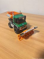 Front three-quarter view of assembled snowplow truck showing cab, blade, spreader