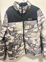 Front view of Levi’s camo puffer jacket showing pattern, logo, pockets and zipper