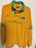 Front view of yellow Wallabies jersey showing logos, flag patch, text