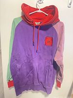 Front view showing color blocking, logo patch, kangaroo pocket