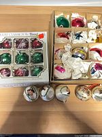 Two boxes of ornaments and five loose printed ornaments displayed on table
