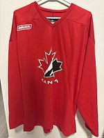 Front view of red Bauer Team Canada practice jersey hanging