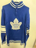 Front view showing team crest, zipper and striping