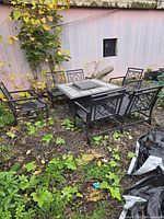 Outdoor metal fire pit dining table with six chairs set photographed outdoors with surrounding foliage