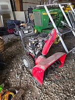 Craftsman red 30-inch snowblower on gravel floor showing full unit, engine, controls, tires and chute