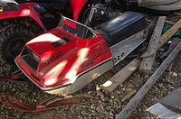 Full view of red Yamaha 576800 snowmobile on ground with skis and seat visible