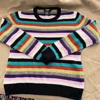 Front view of striped cashmere sweater laid flat