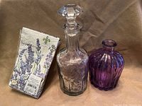 Group shot of decanter with bath salts, purple diffuser bottle and pack of lavender paper towels