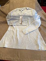 Full view of iced grey sweater laid flat showing overall design and long sleeves