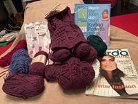 Assorted yarn skeins, knitting books and magazine