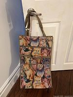 Front view of cat tapestry shopping cart hanging from door handle