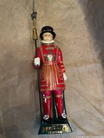 Front view of full ceramic Beefeater figurine showing uniform details and base lettering