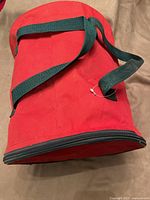 Exterior view of red cylindrical storage bag with green handles