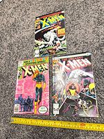 All three X-Men comics laid out with measuring tape for scale