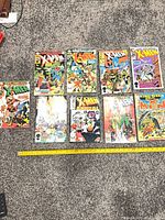 Nine X-Men Annual comics laid out on carpet with measuring stick for scale