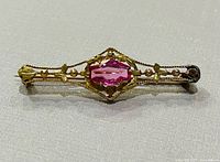 Full view of gold brooch with pink stone