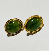 front view of both oval green stone earrings in gold settings