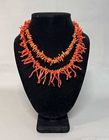 Front view of both coral branch necklaces on display bust