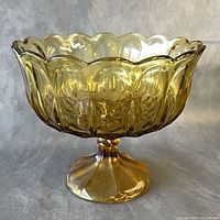 Side view of amber pressed glass footed bowl showing scalloped rim and pedestal base