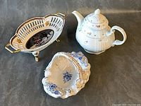 Group shot of three porcelain items: teapot, reticulated bowl, triangular bowl
