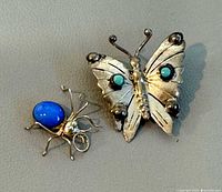 Front view of butterfly brooch and spider pendant showing stones and overall design