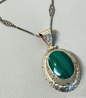 Close-up of pendant showing malachite stone, hammered silver bezel and bail