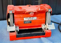 Full view of red bench grinder showing both grinding wheels and housing