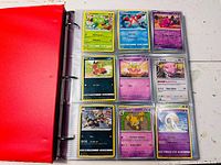 Binder open showing nine Pokémon cards in plastic page