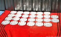 Overview of all 26 Royal Albert Petit Point plates arranged on red cloth