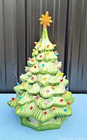 Front view of green ceramic Christmas tree with multicolour bulbs and star topper
