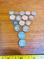 Full group of approximately 15 Canadian silver dimes displayed on wooden surface with ruler for scale