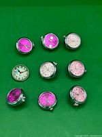 Nine snap watch buttons laid out on green background