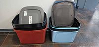Two stacks of assorted plastic storage totes with lids