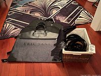 Belts in basket, ties and garment bag displayed on floor