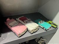 Four die-cast cars lined up on shelf