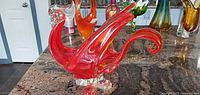 Right side view of red and clear blown glass swan figurine on countertop