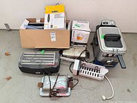 Group shot showing all appliances including boxed items, deep fryer, roller grill, vintage iron