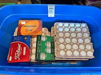 Blue tote containing boxed and loose white golf balls on cardboard trays