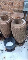 Pair of large terracotta urns with small black plastic planter in front