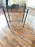 Full angled view of black 3-tier wire shelving rack showing all shelves and posts
