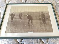 Full view of framed golf photograph showing four golfers, teal frame, off-white mat