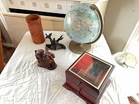 All six items arranged: globe, vase, metal bookends, carved wood sculpture, jewelry box, lampshade parts (partial)