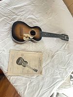 Soprano sunburst ukulele with instruction sheet on white surface