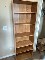 Front view of tall light oak laminate bookcase showing six shelf spaces