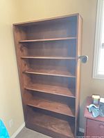 Front view of tall wooden bookcase showing six shelves and stain color