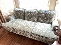 Front view of light sage damask three-seat sofa showing tufted back and separate seat cushions