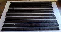 Ten black bristle brush strips laid out horizontally